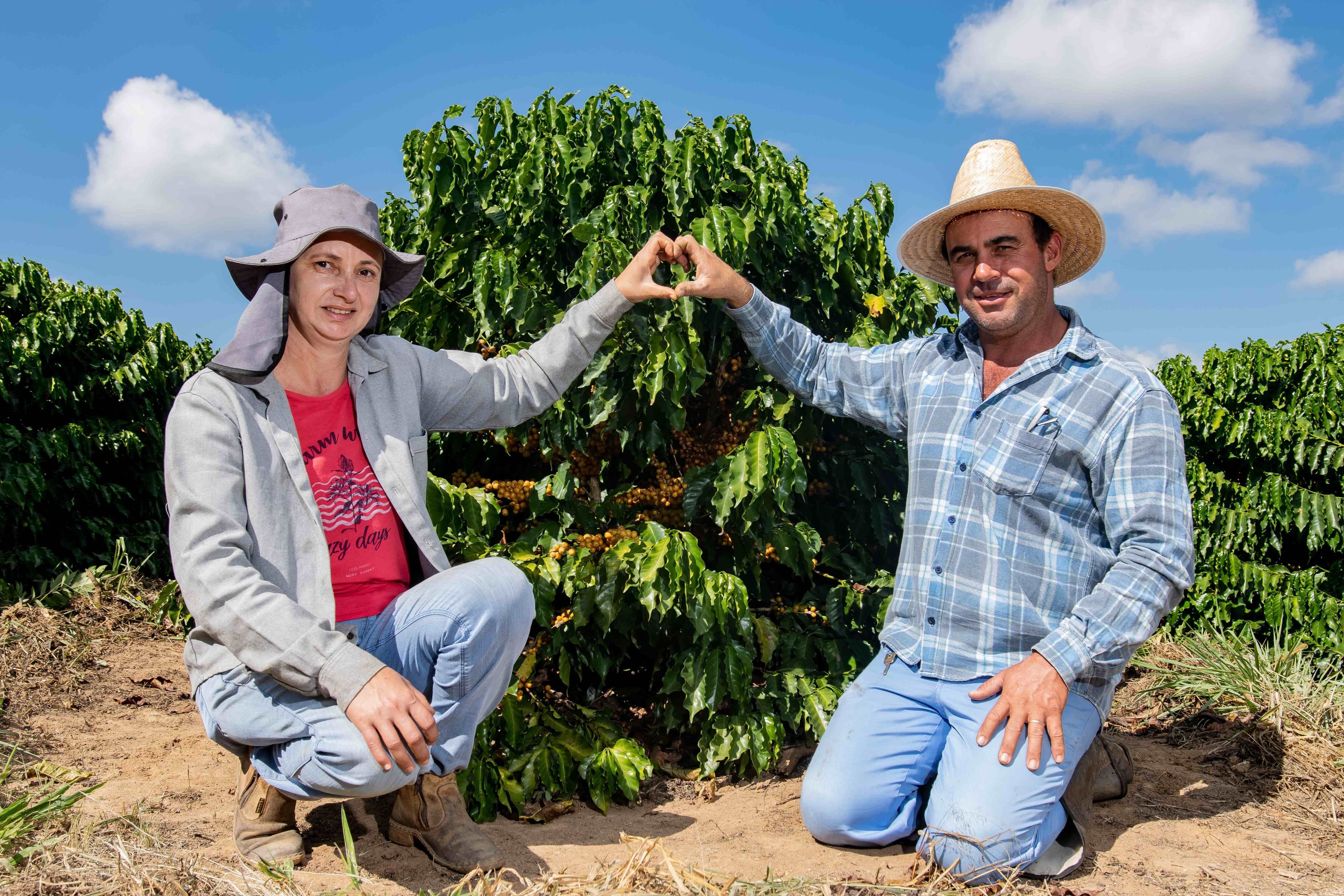 Presentation on sustainable and inclusive transitions in coffee-growing regions. Mr. Neumann stands at a podium delivering a presentation beside a large screen displaying the title “Coffee Regions in Transition: Sustainability and Inclusion” at an indoor event. The stage is decorated with green ferns and attended by several people.